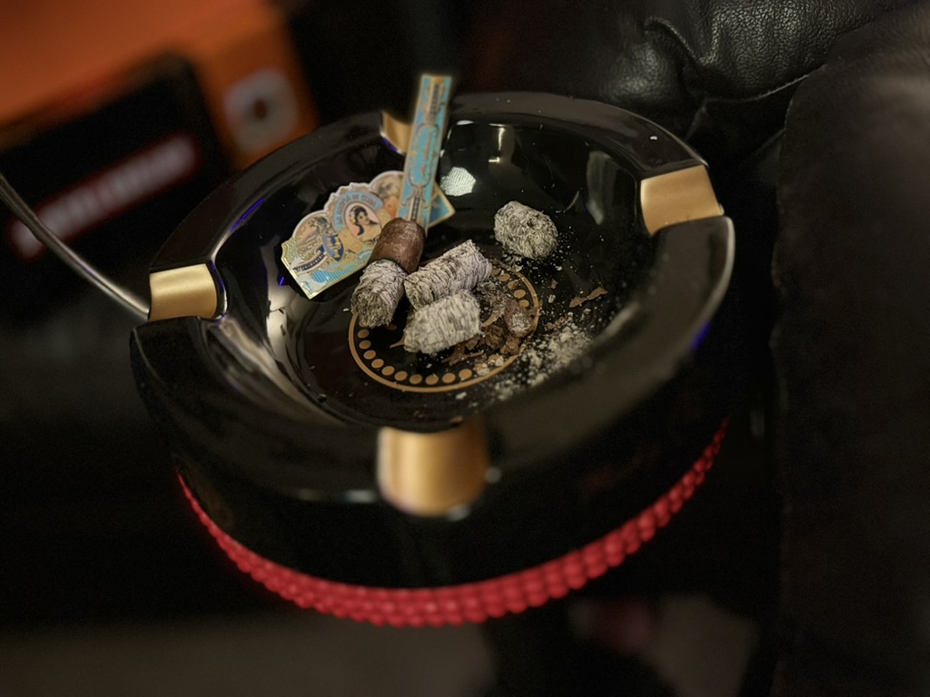 Finished La Aroma de Cuba Mi Amor Toro nub resting in a Rocky Patel ashtray surrounded by ash and removed cigar bands after a complete smoking session.