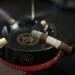 Rocky Patel LB1 Robusto burning with a clean, firm ash while resting on a black Rocky Patel ashtray.