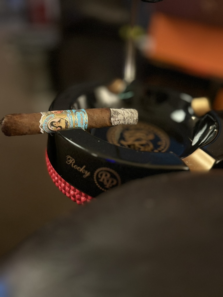 La Aroma de Cuba Mi Amor Toro resting across a black Rocky Patel ashtray during the first third with a straight burn and compact white ash.