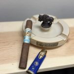 La Aroma de Cuba Mi Amor Toro resting beside a blue My Father torch lighter and Buffalo Trace ashtray before being lit.