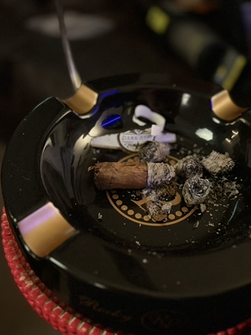 Rocky Patel Dark Star Robusto nub and scattered ash in a black Rocky Patel ashtray.