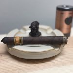 Unlit Nica Rustica Connecticut Broadleaf Toro resting across a ceramic ashtray on a wooden surface