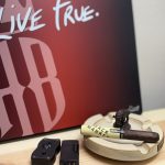 Alec Bradley Black Market Toro resting in an ashtray with cutter and lighter in front of an Alec Bradley Live True sign