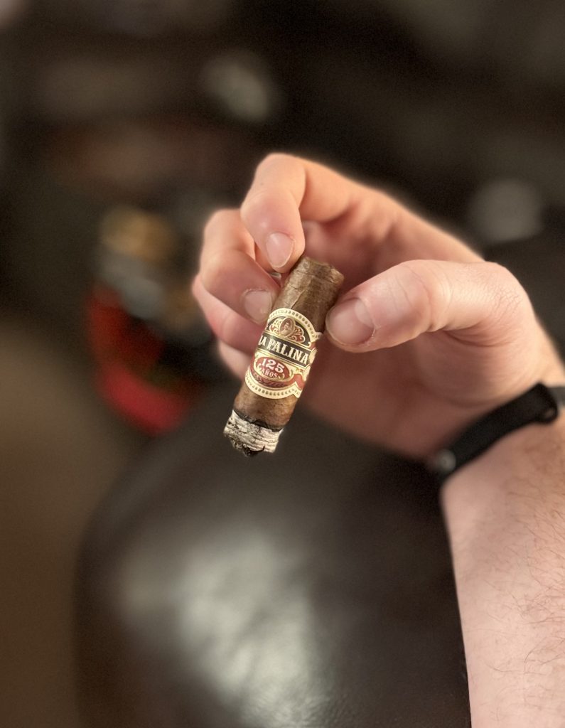 Smoker holding the La Palina 125 Años Toro during the first third with a compact white ash forming.