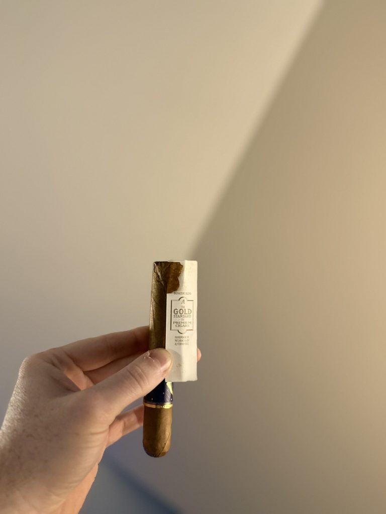 Close-up of the AJ Fernandez Amar Toro showing the removed decorative gold foot band that pulled wrapper leaf away from the cigar.