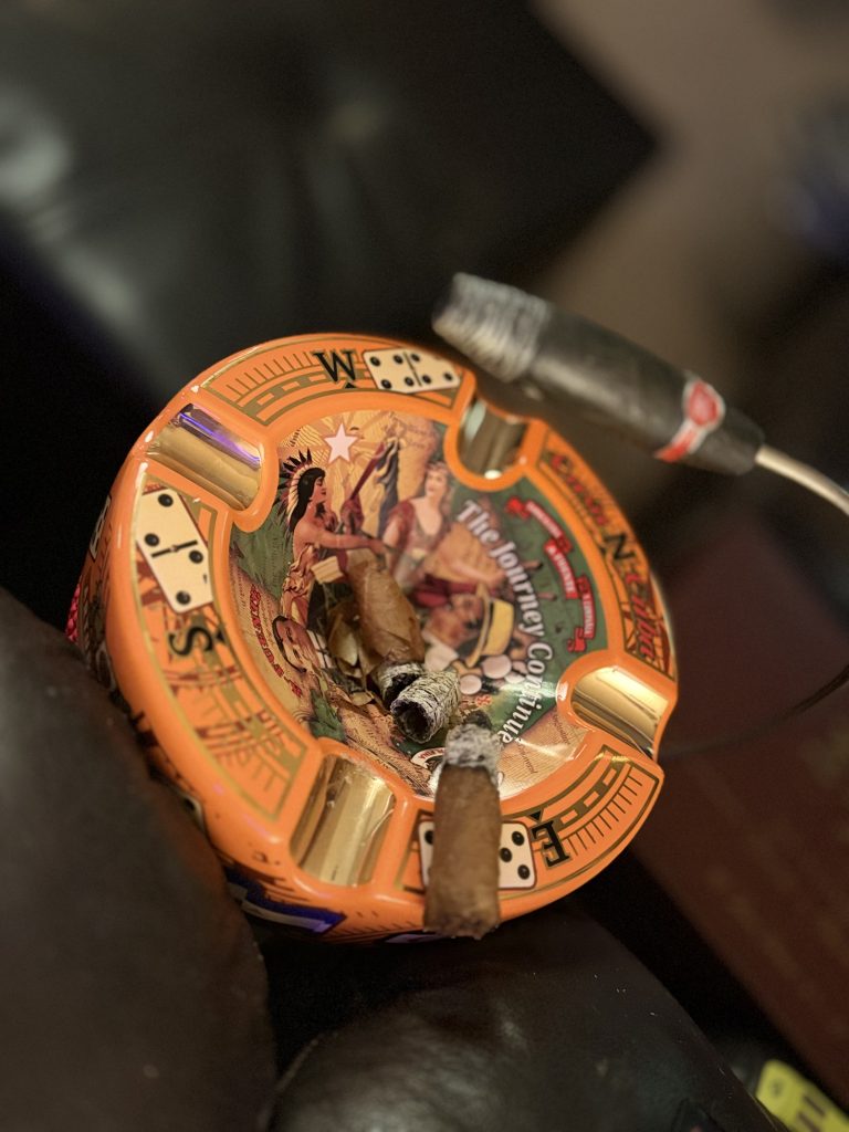 AJ Fernandez Amar Toro resting in an orange Arturo Fuente ashtray after the wrapper completely unraveled, alongside the separated wrapper leaf.