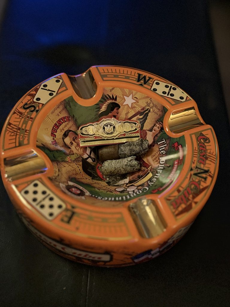 Finished Arturo Fuente Reserva Don Carlos Robusto resting in a Casa Cuba ashtray beside the removed cigar band.