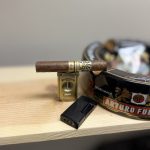 Ferio Tego Timeless Panamericana Epicure resting on a cigar cutter beside an Arturo Fuente ashtray before lighting.
