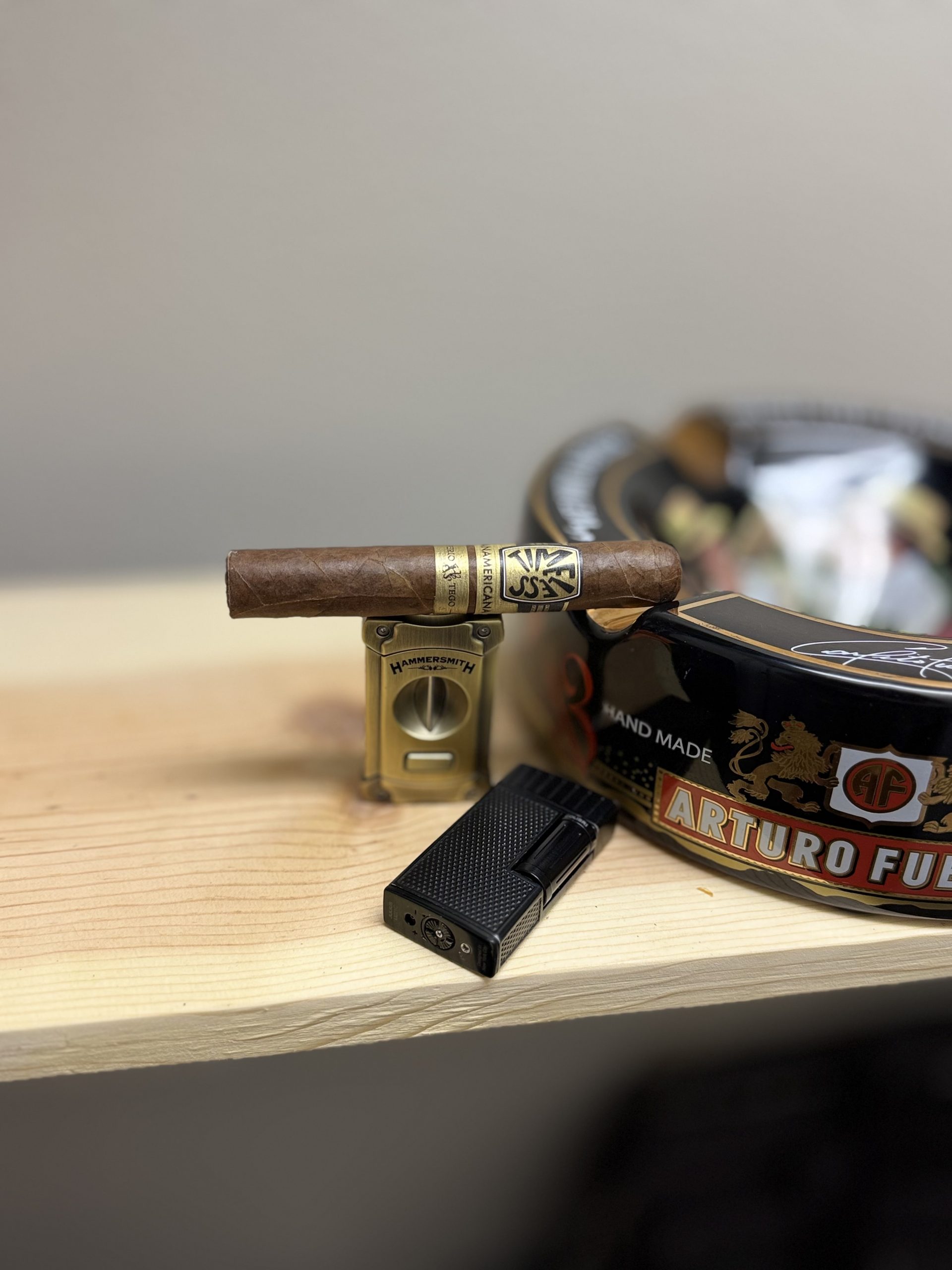 Ferio Tego Timeless Panamericana Epicure resting on a cigar cutter beside an Arturo Fuente ashtray before lighting.