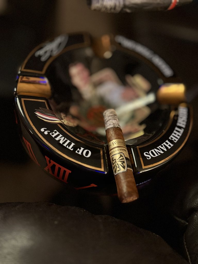 Lit Ferio Tego Timeless Panamericana Epicure resting across an Arturo Fuente ashtray with a long ash.