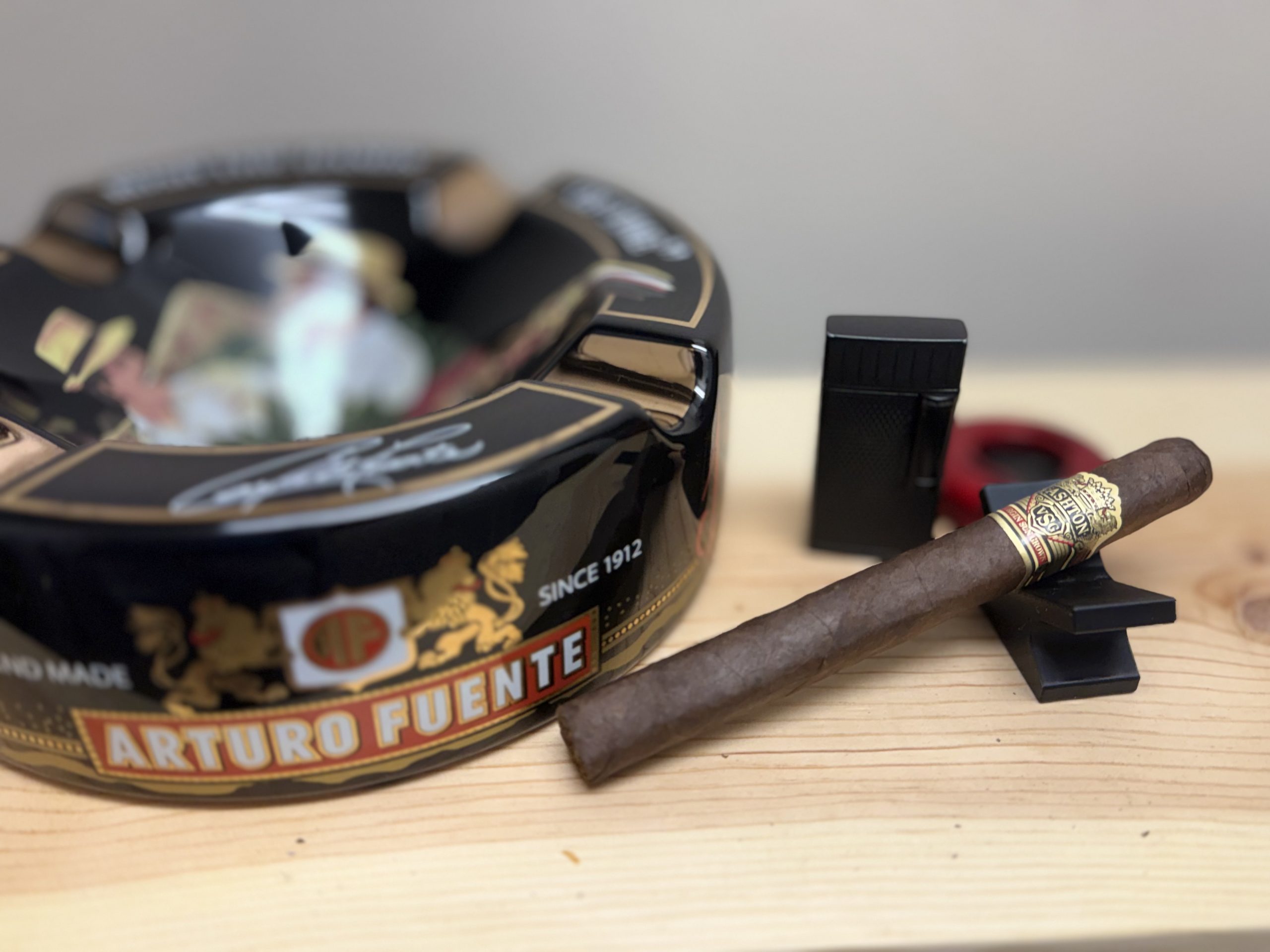 Ashton VSG Sorcerer cigar resting beside a black Arturo Fuente ashtray and black lighter.