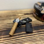 Aladino Connecticut Robusto cigar resting beside a black guillotine cutter and lighter before smoking.