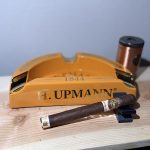 H. Upmann 180 Anniversary Churchill cigar resting beside an orange H. Upmann 1844 ashtray before lighting.