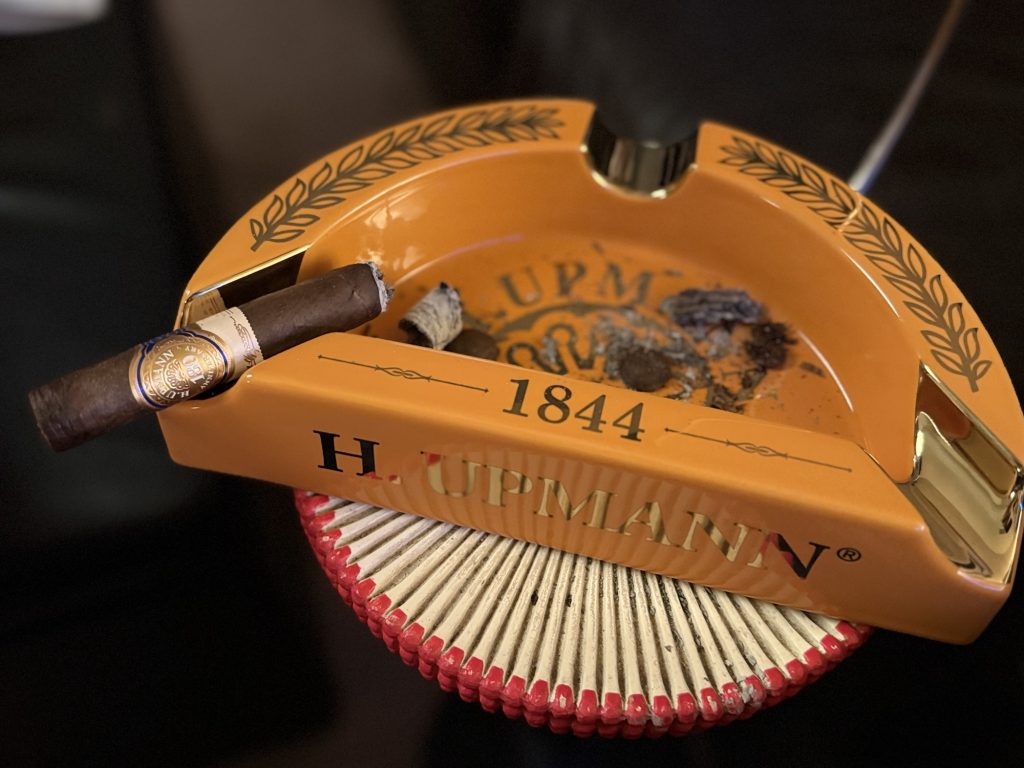 H. Upmann 180 Anniversary Churchill in its final third resting on an H. Upmann ashtray surrounded by fallen ash.
