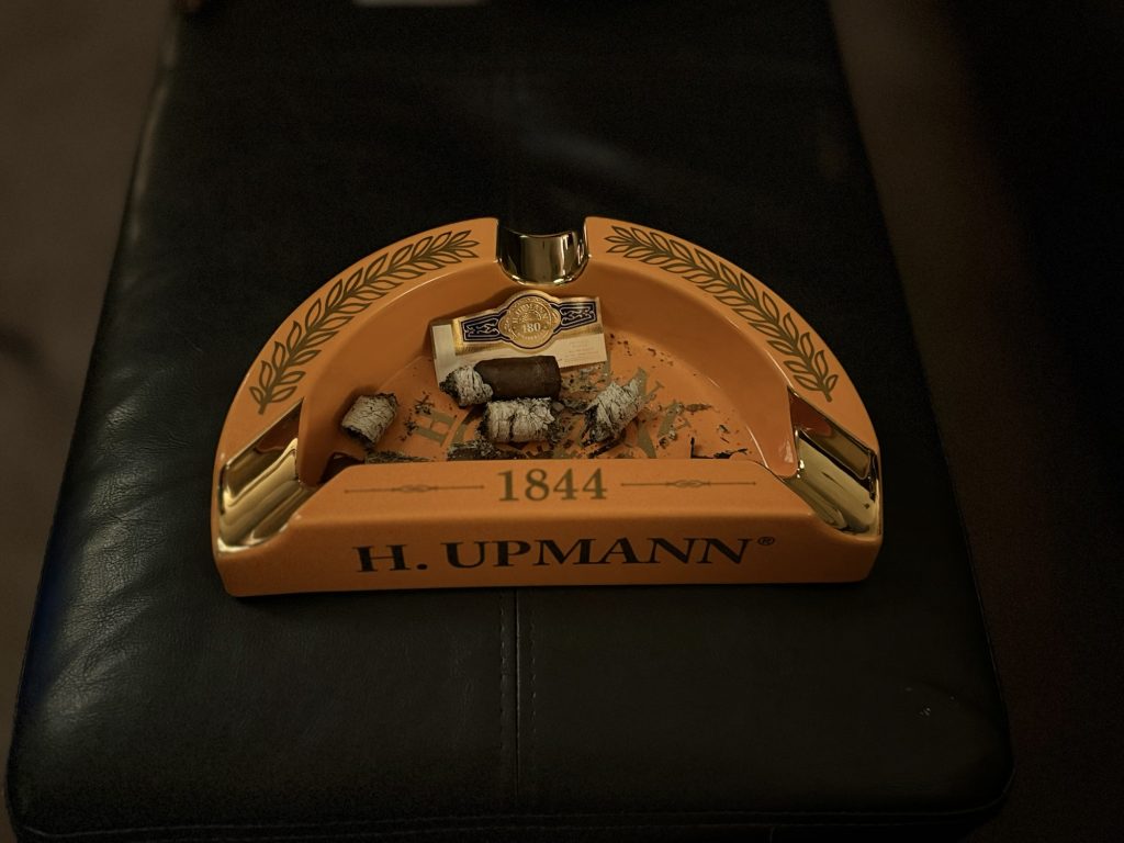 Finished H. Upmann 180 Anniversary Churchill nub, ash and removed anniversary band inside an orange H. Upmann ashtray.