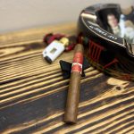 Romeo y Julieta 1875 Miami Deco Toro resting on a black cigar stand beside an ashtray and lighter.
