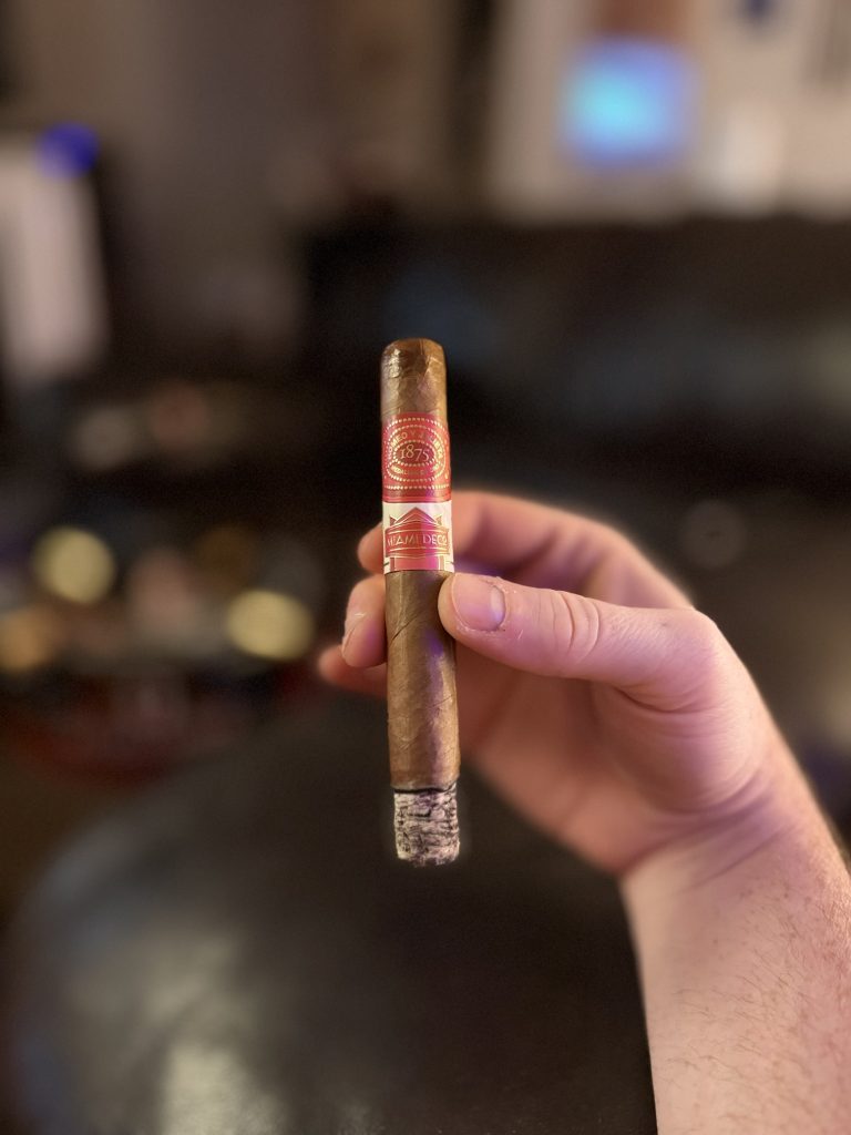Lit Romeo y Julieta 1875 Miami Deco Toro held upright with an intact ash during the smoking session.