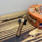 Unlit AVO Classic Natural Robusto resting on a black cigar stand beside an orange Cuban-themed ashtray.