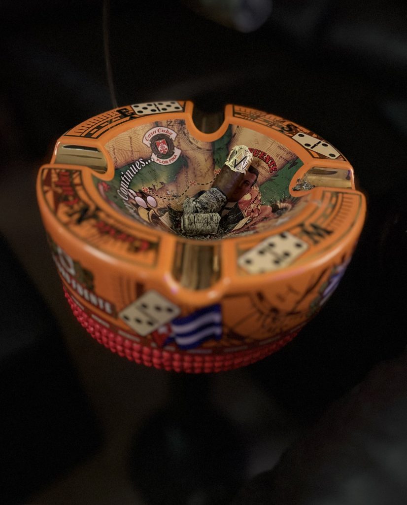 Final nub of an AVO Classic Natural Robusto standing in an orange Cuban-themed ashtray among cigar ash.