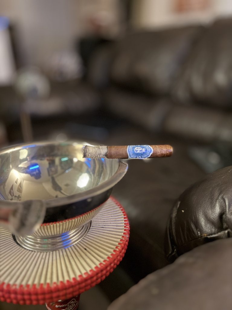 Crowned Heads Moonflower Corona Gorda resting across a polished metal ashtray with a long gray ash during the smoke.