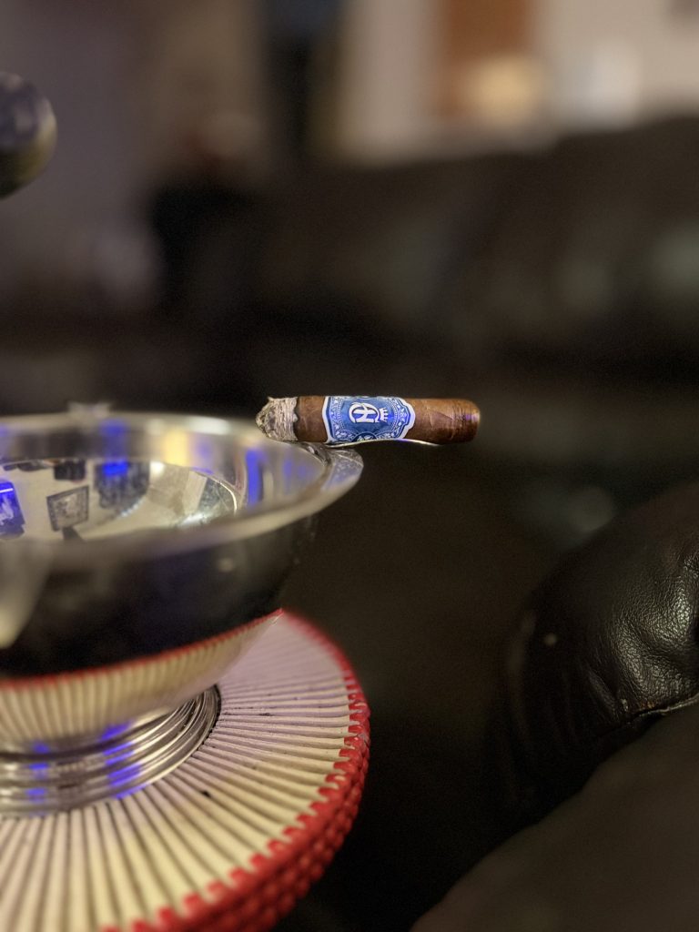 Crowned Heads Moonflower Corona Gorda resting on an ashtray late in the smoke with the primary blue Crowned Heads band remaining.