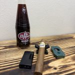 Lure Cigars Tally Allie Habano Toro beside a glass bottle of cane-sugar Dr Pepper, lighter and cigar cutter.