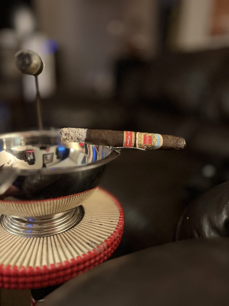 Lit E.P. Carrillo La Historia III resting across a silver ashtray with a long intact ash.
