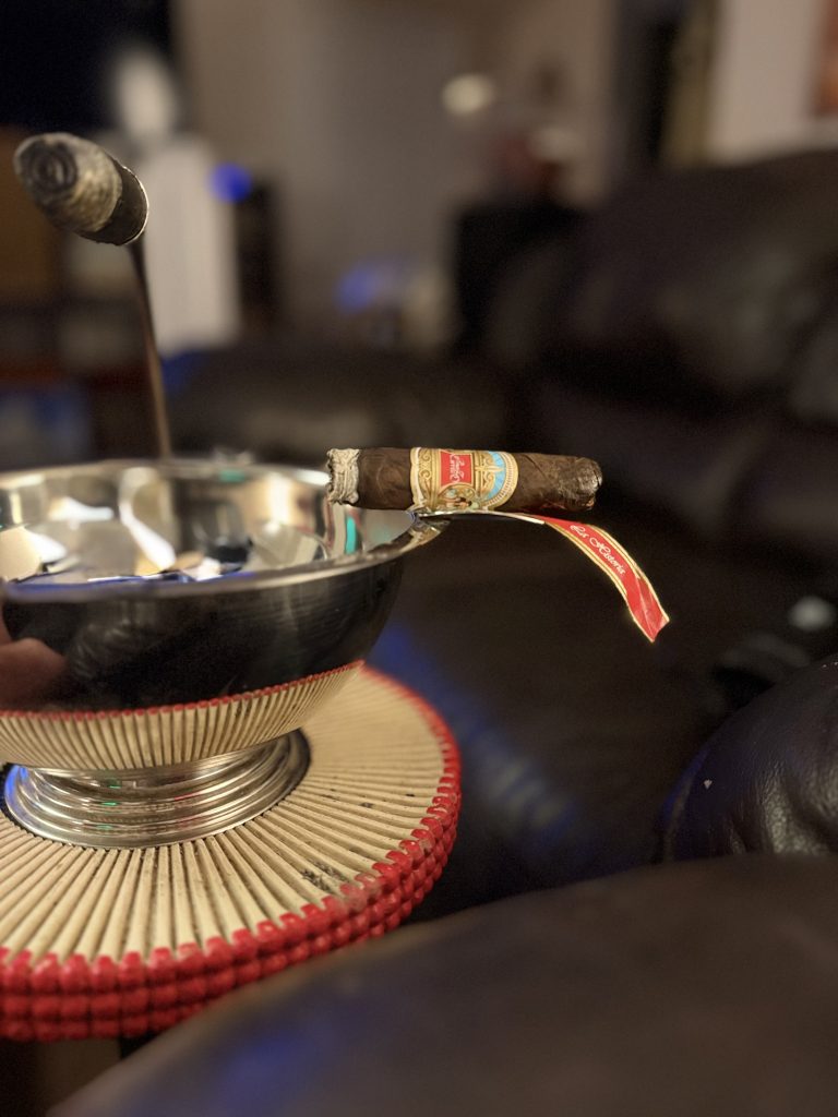 E.P. Carrillo La Historia III resting on a silver ashtray as the red secondary band is removed.