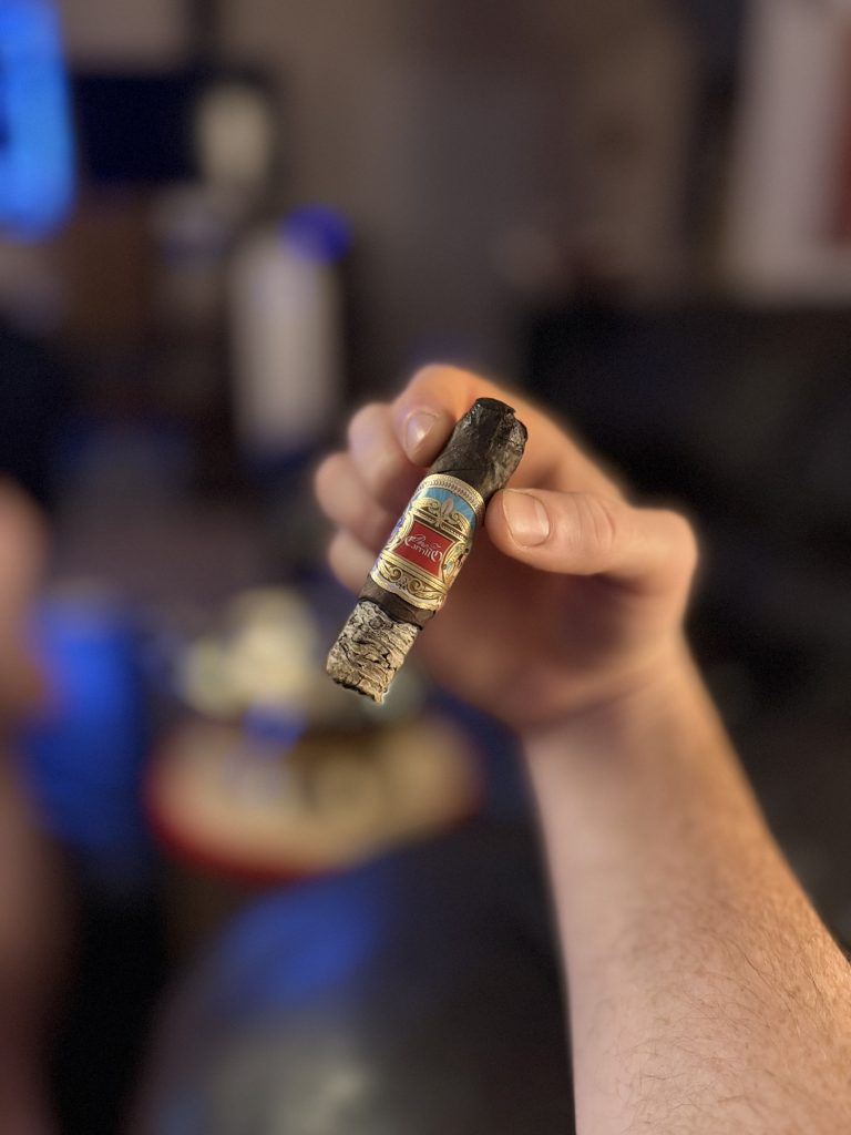 Final portion of the E.P. Carrillo La Historia III held by hand with a thick ash and primary band remaining.