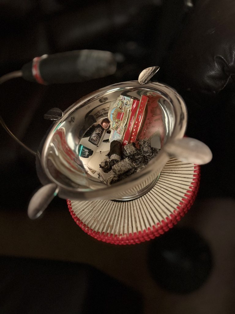 Finished E.P. Carrillo La Historia III resting in a silver ashtray beside its removed cigar bands and accumulated ash.